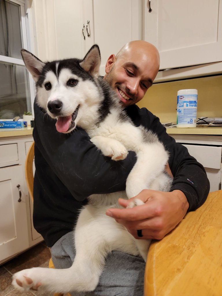 Tor holding Rosé as a puppy in the kitchen