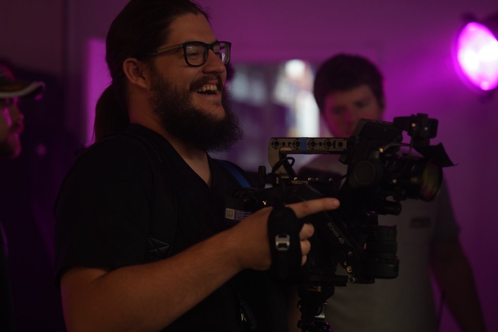DP smiling holding camera in purple light