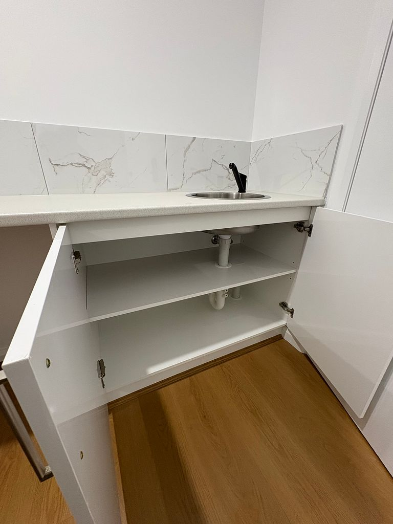 Open cabinetry and sink unit detailing after a builders clean