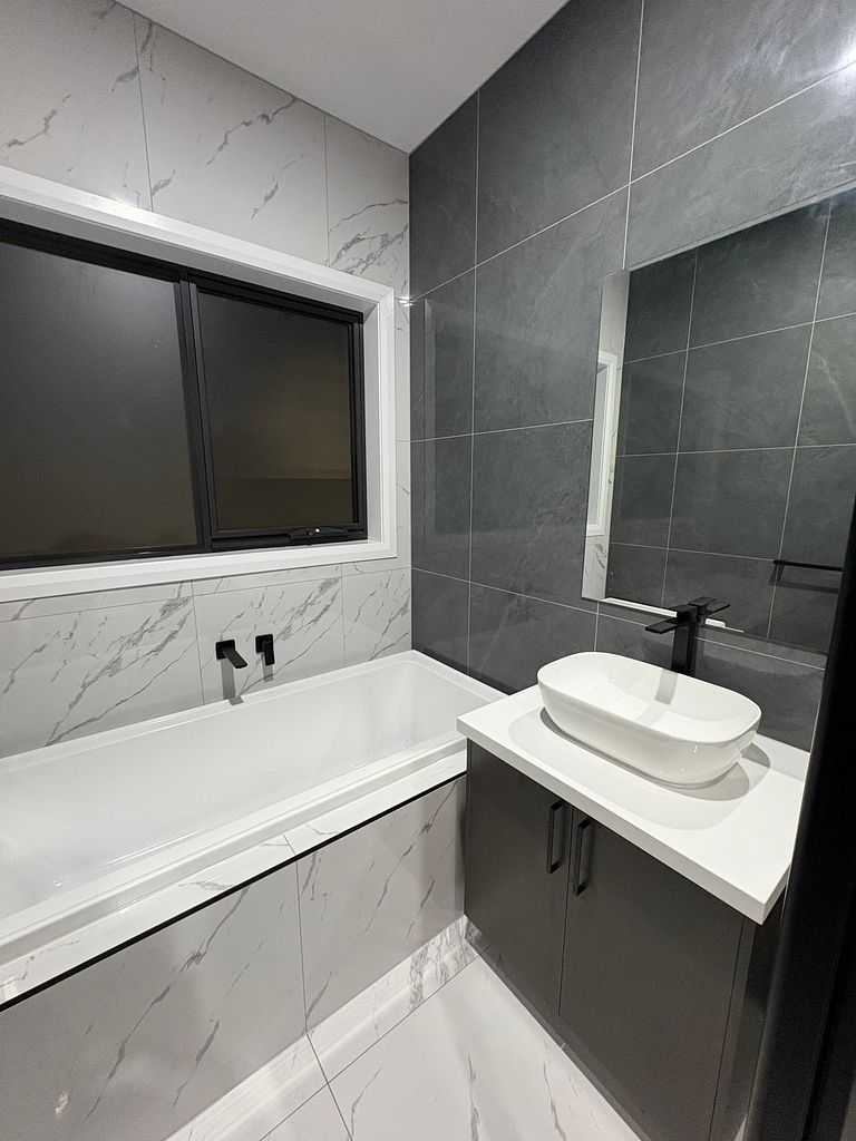 Finished bathroom with freestanding bath, vanity and marble tiling after a builders clean