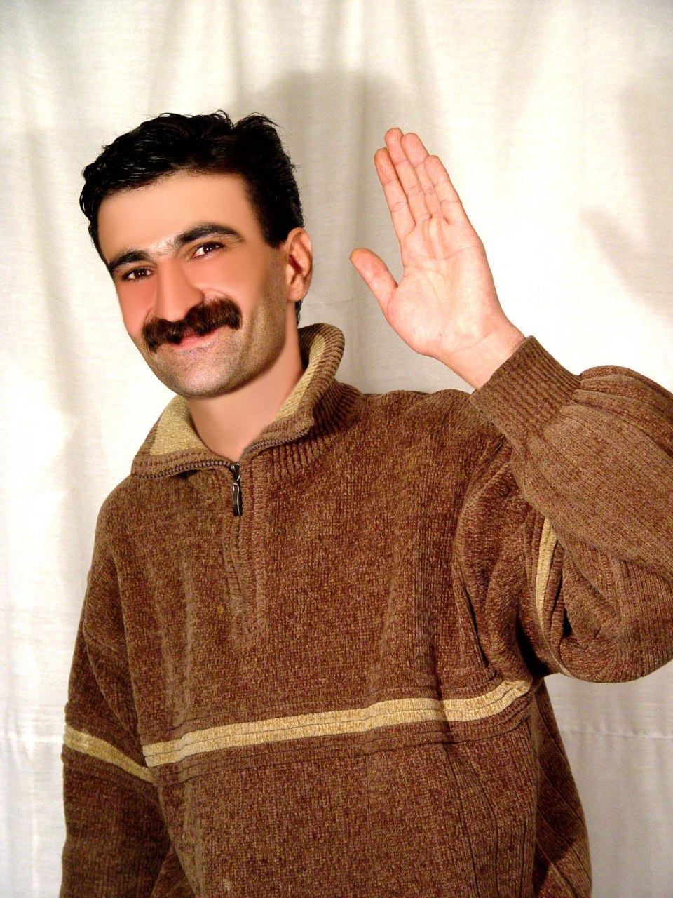 حمید حمیدی با لبخند و لباس قهوه‌ای