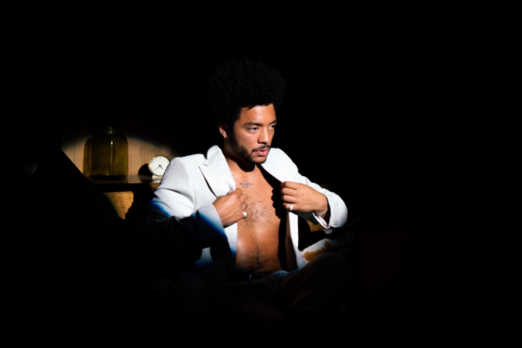 Felix Ames adjusting cream suit jacket, dramatic spotlight