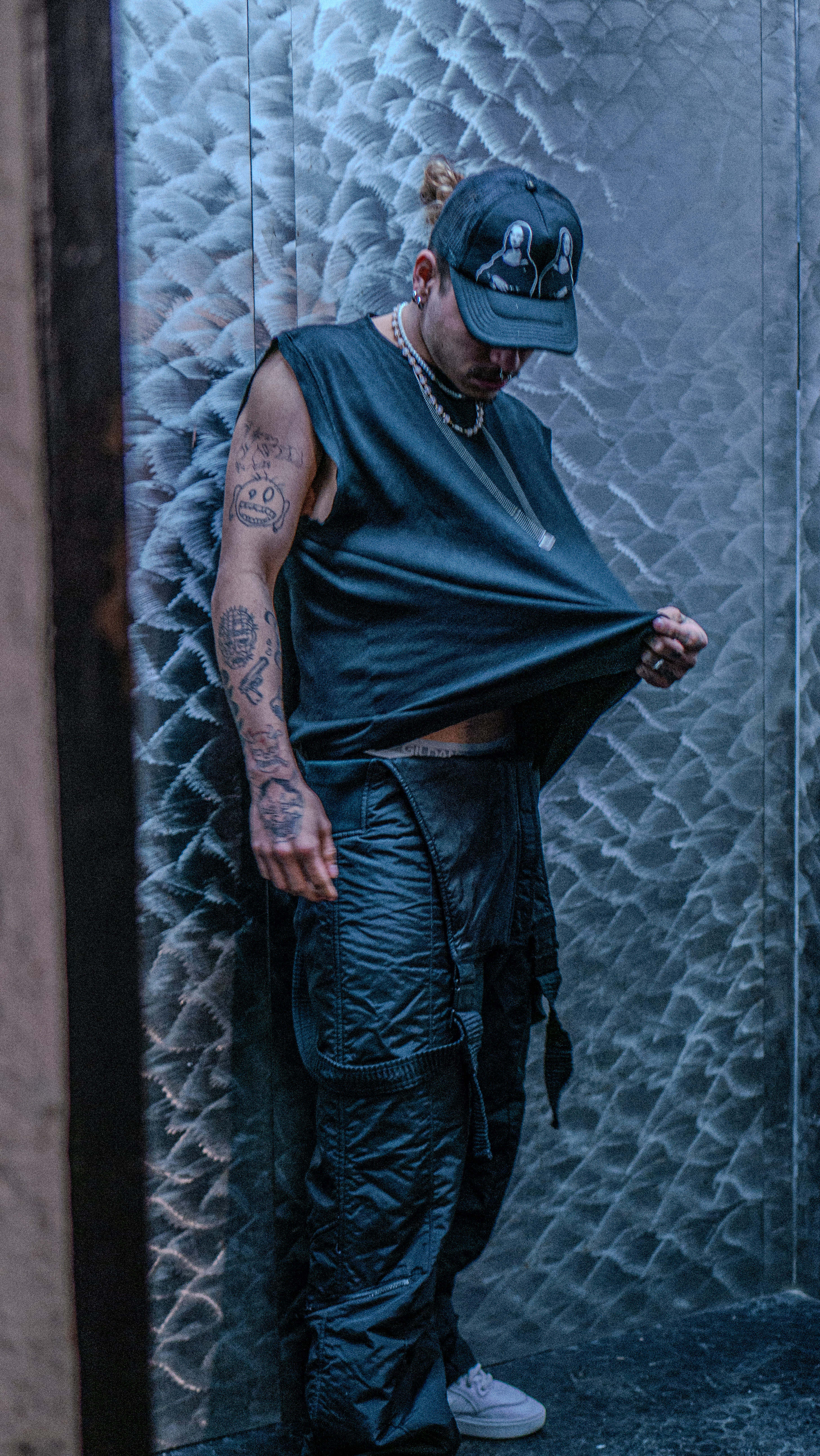 Devincii — cargo pants and sleeveless tee, textured backdrop