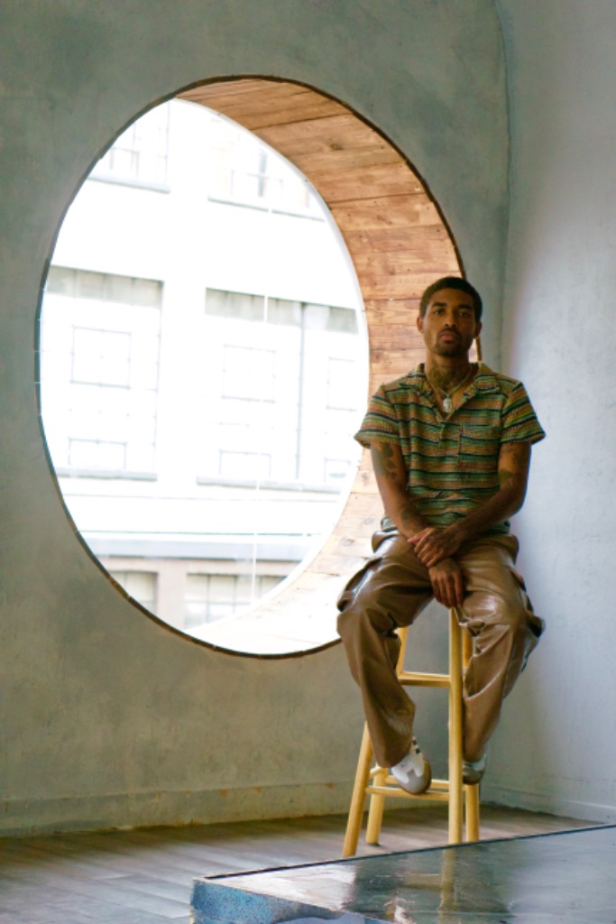 Forest Ripperton seated on stool in front of circular window