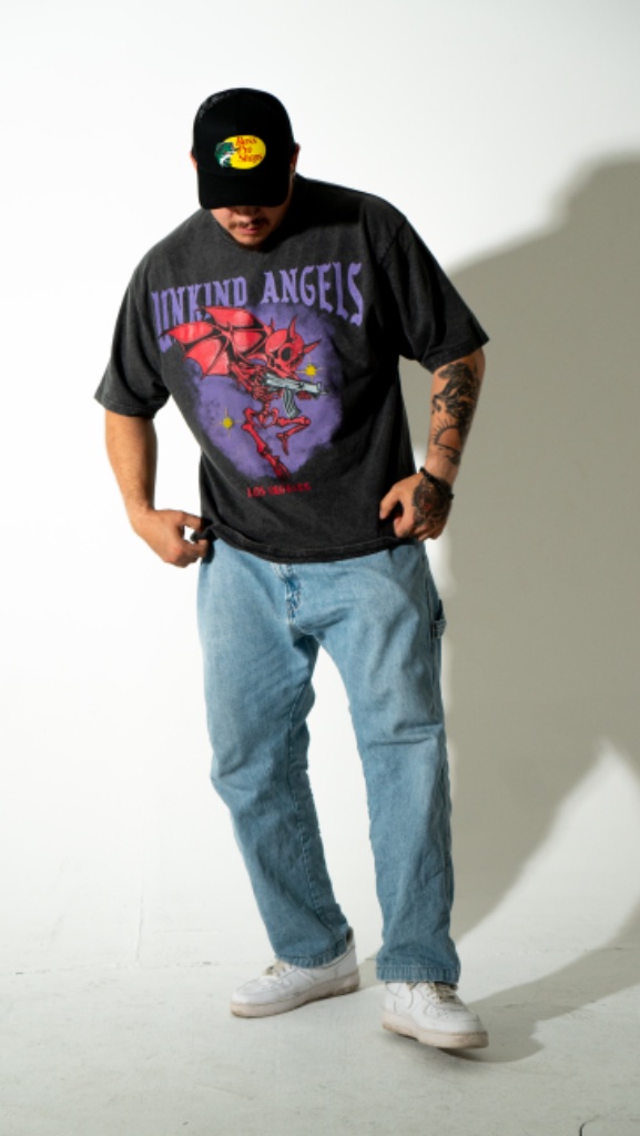Tattooed male model in graphic tee posing, white studio backdrop