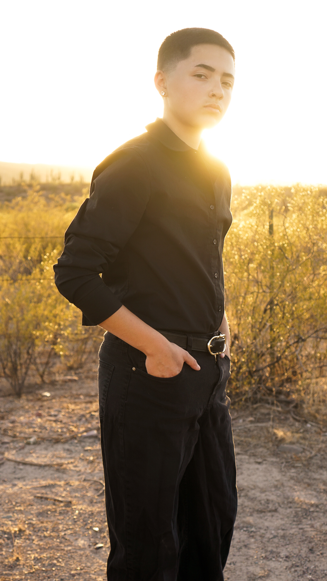 Young man in black outfit posing in golden desert landscape