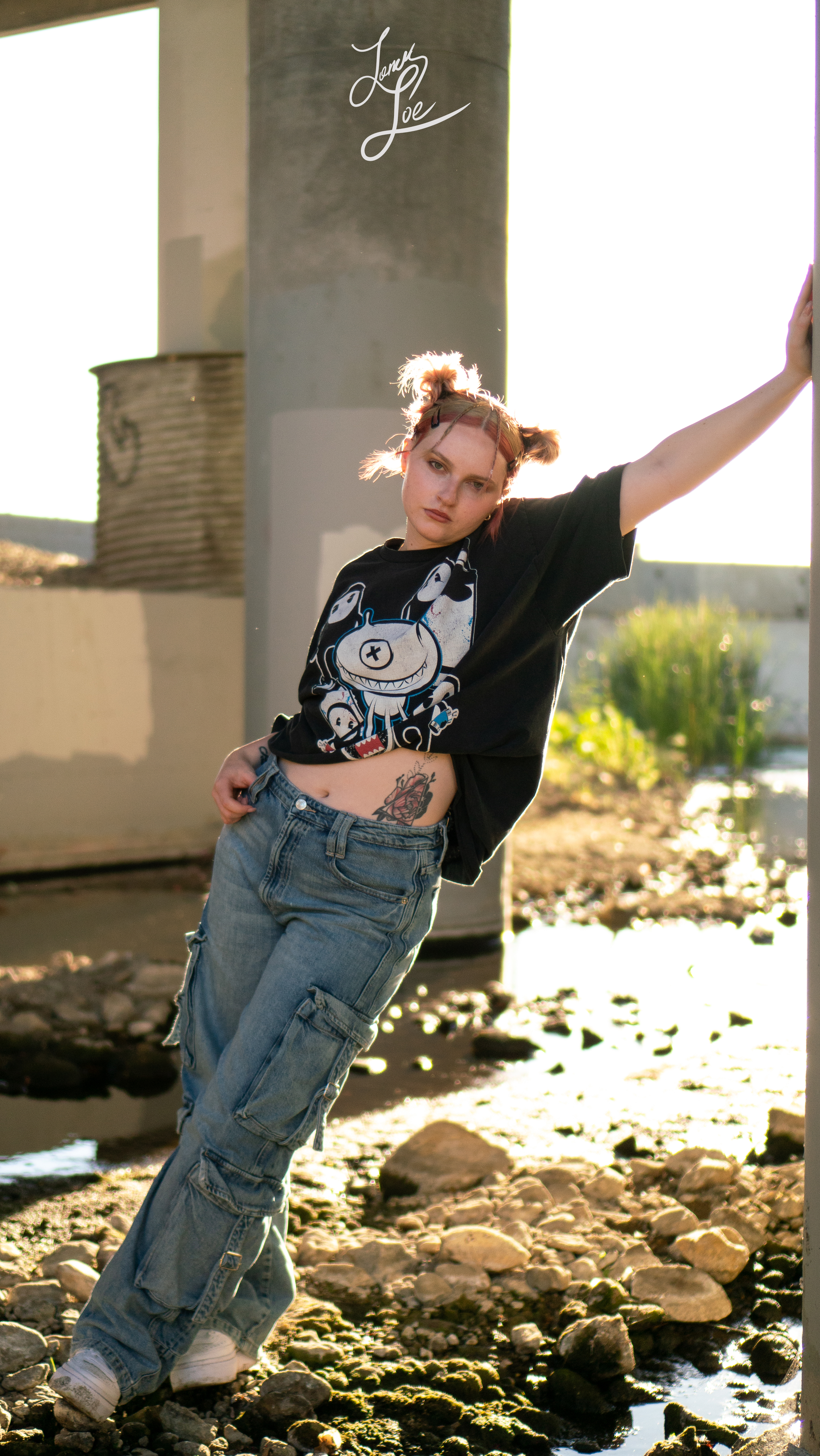 Woman leaning against concrete pillar, graphic tee and wide-leg cargo jeans