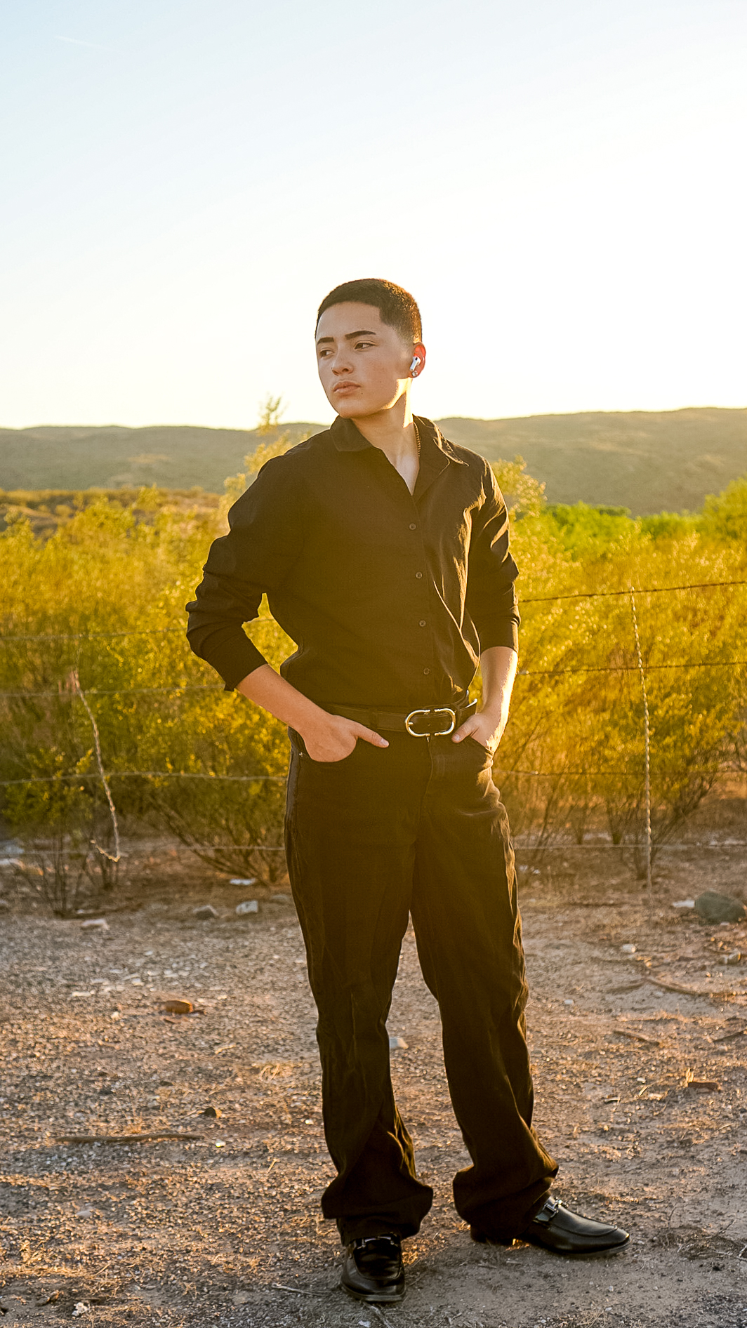 Young man in black shirt standing in desert landscape at golden hour