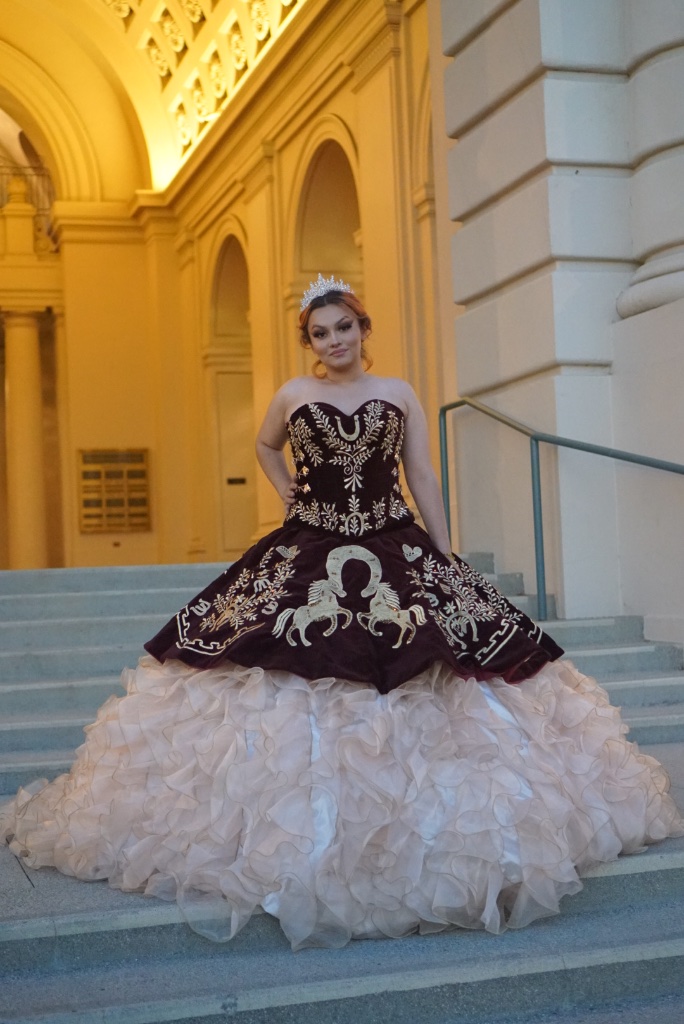 Quinceañera portrait in an ornate ball gown on grand steps