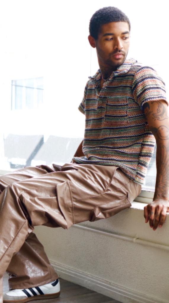 Forest Ripperton seated on windowsill in striped polo and cargo pants