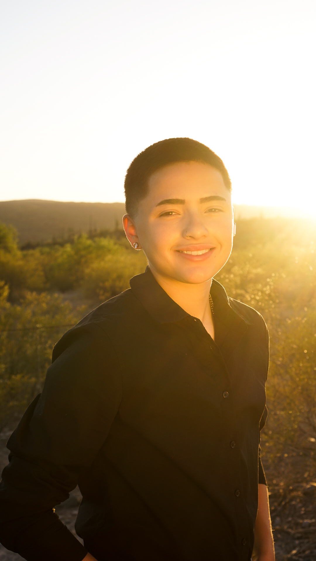 Smiling young man with sun flare in desert at golden hour