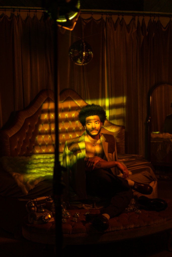 Felix Ames on gold bed with disco ball and ornate mirror
