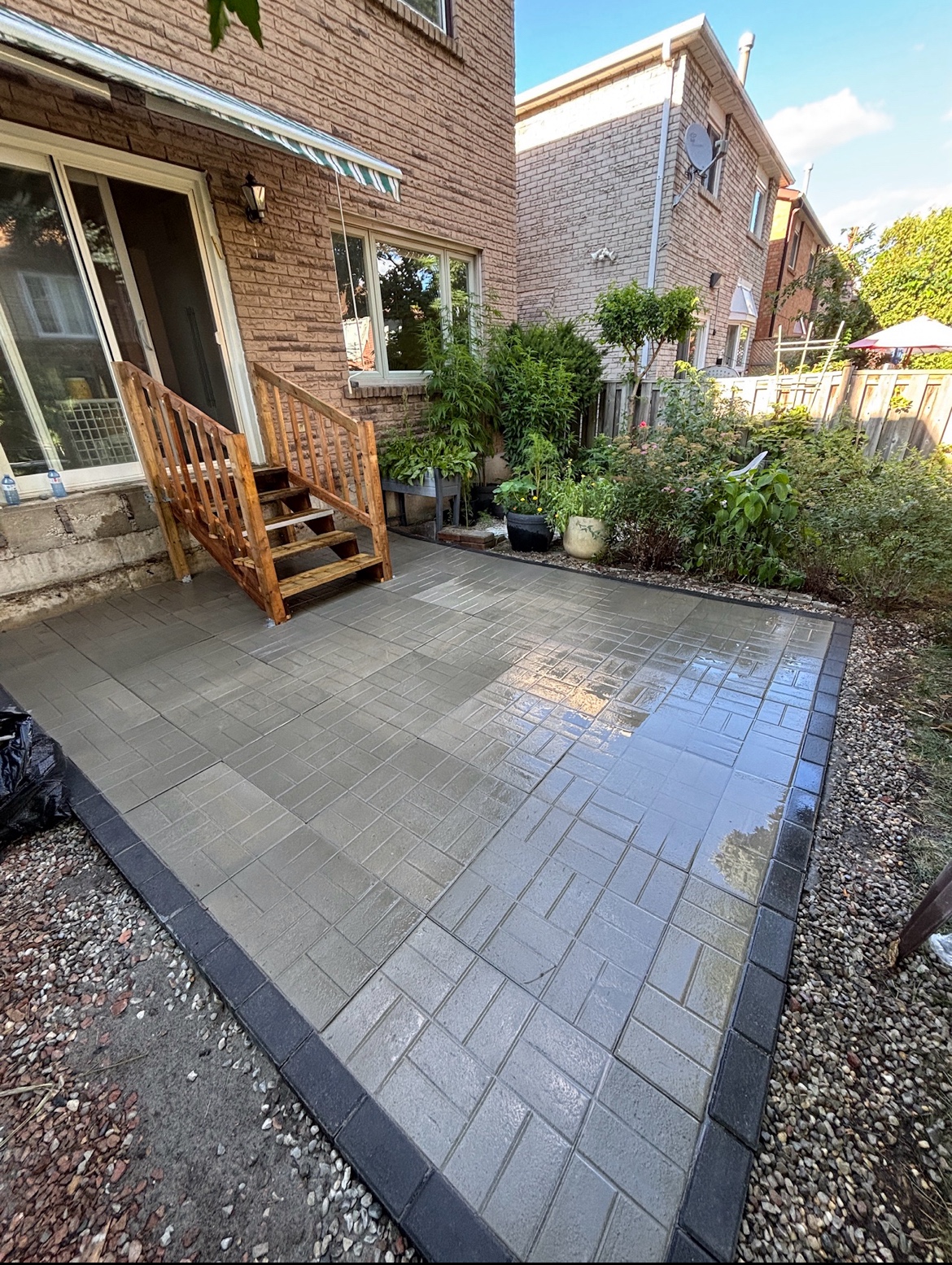 Freshly installed gray interlocking concrete pavers in a staggered running-bond pattern with a dark charcoal border