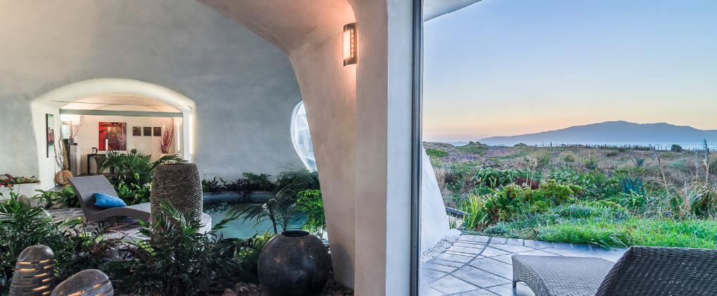 Indoor-outdoor living space with pool and coastal view at golden hour