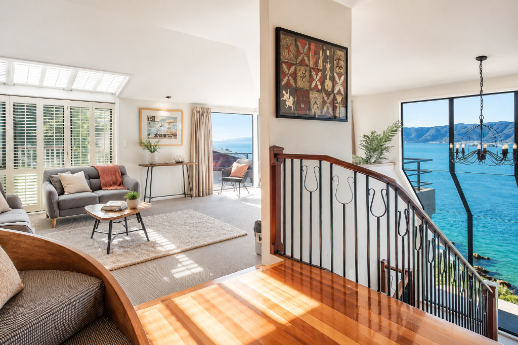 Bright open-plan interior with ocean view and wrought-iron staircase
