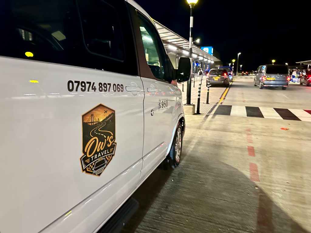 Ow's Travel minibus at airport drop-off at night