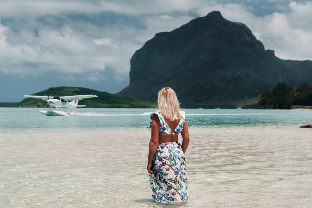 Traveler standing in turquoise ocean waters near a seaplane