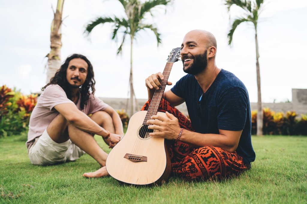 Two travelers relaxing with a guitar in a tropical garden