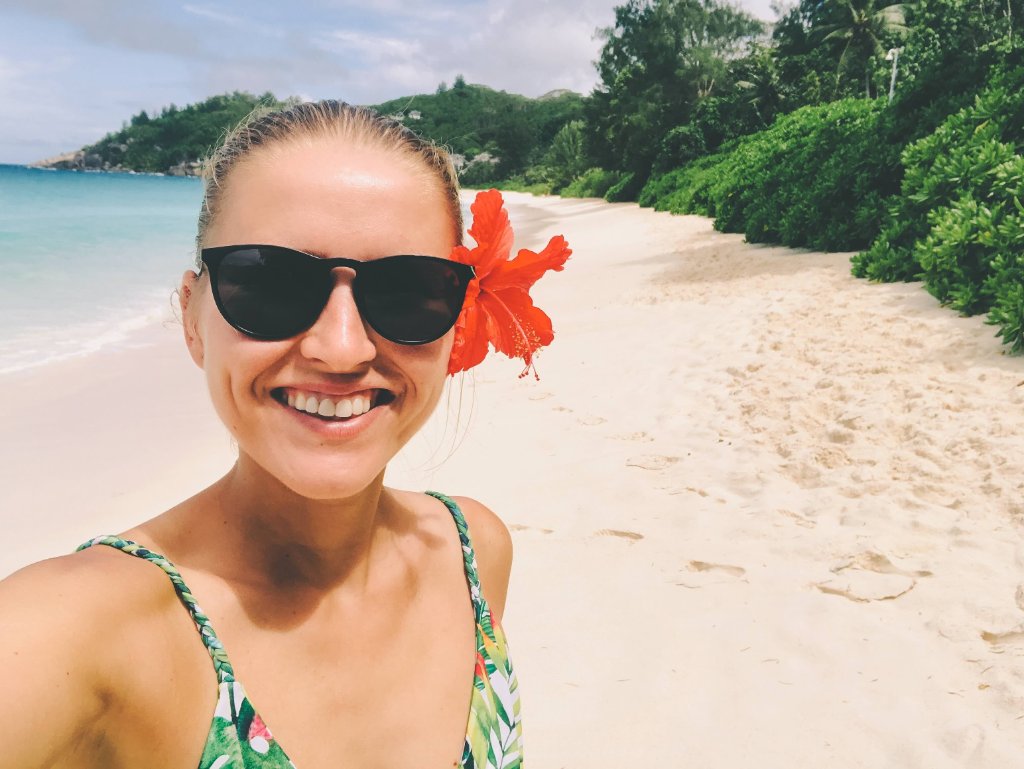 Traveler smiling at the beach with a hibiscus flower