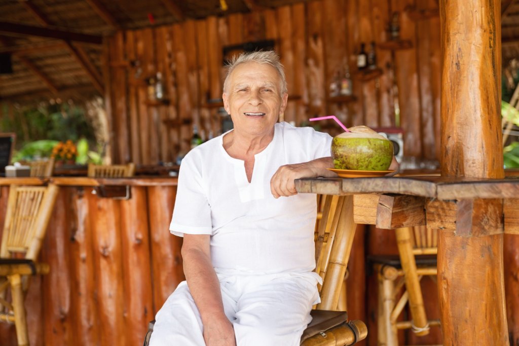 Senior traveler enjoying fresh coconut water at a beach bar