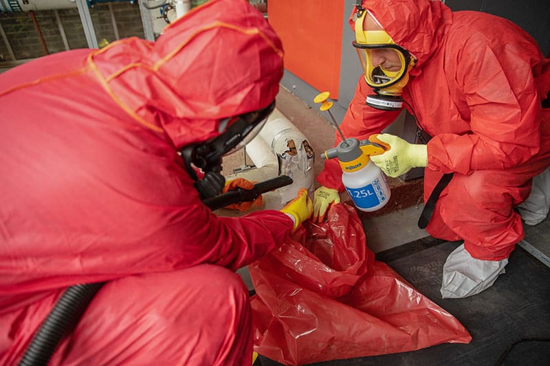 Asbestos removal operatives in protective suits