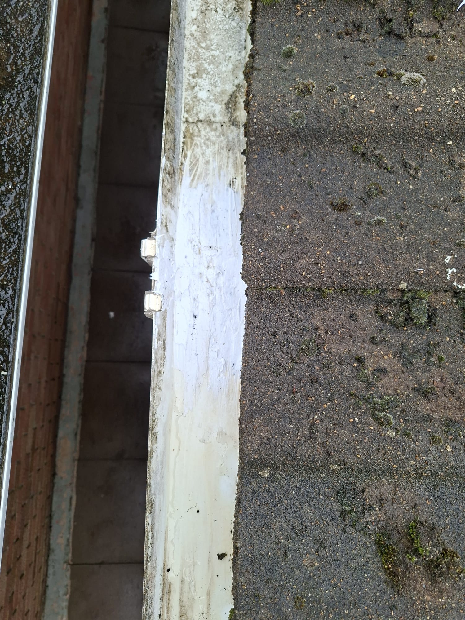 Repaired and sealed white uPVC gutter joint beside a moss-covered tiled roof in Stanground, Peterborough