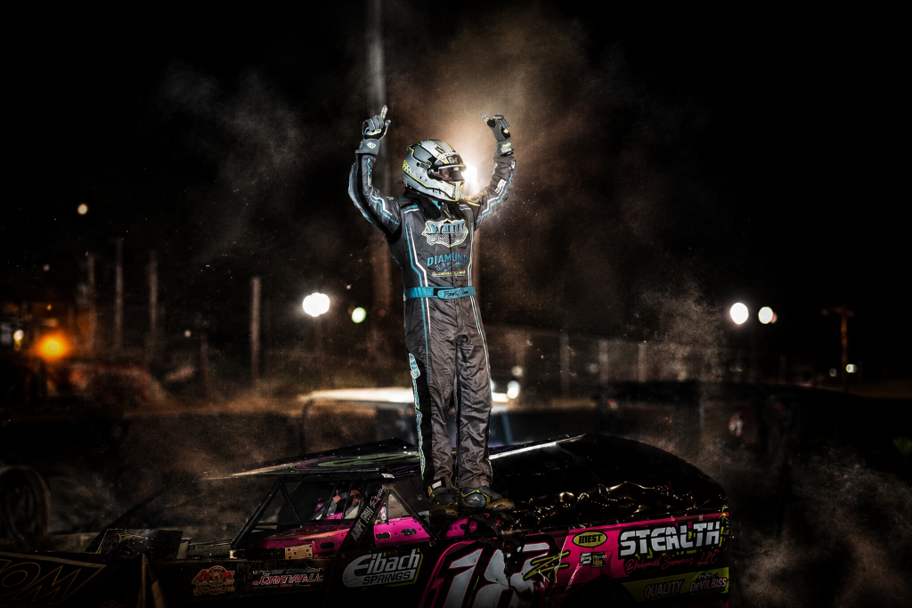 Zane DeVilbiss in victory lane standing on his race car