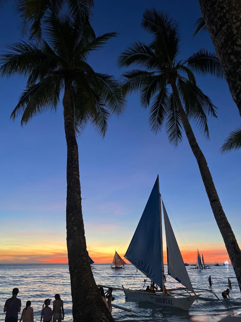 Sunset on Boracay beach with outrigger sailboats