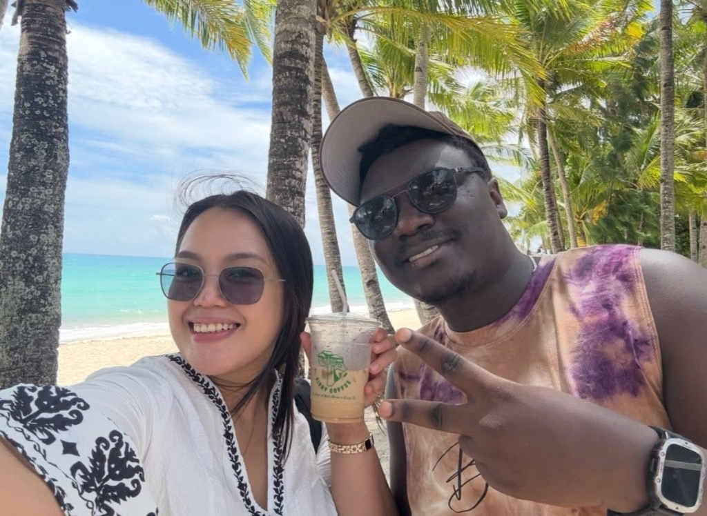 Two customers holding Sisay Coffee cups on the beach in Boracay
