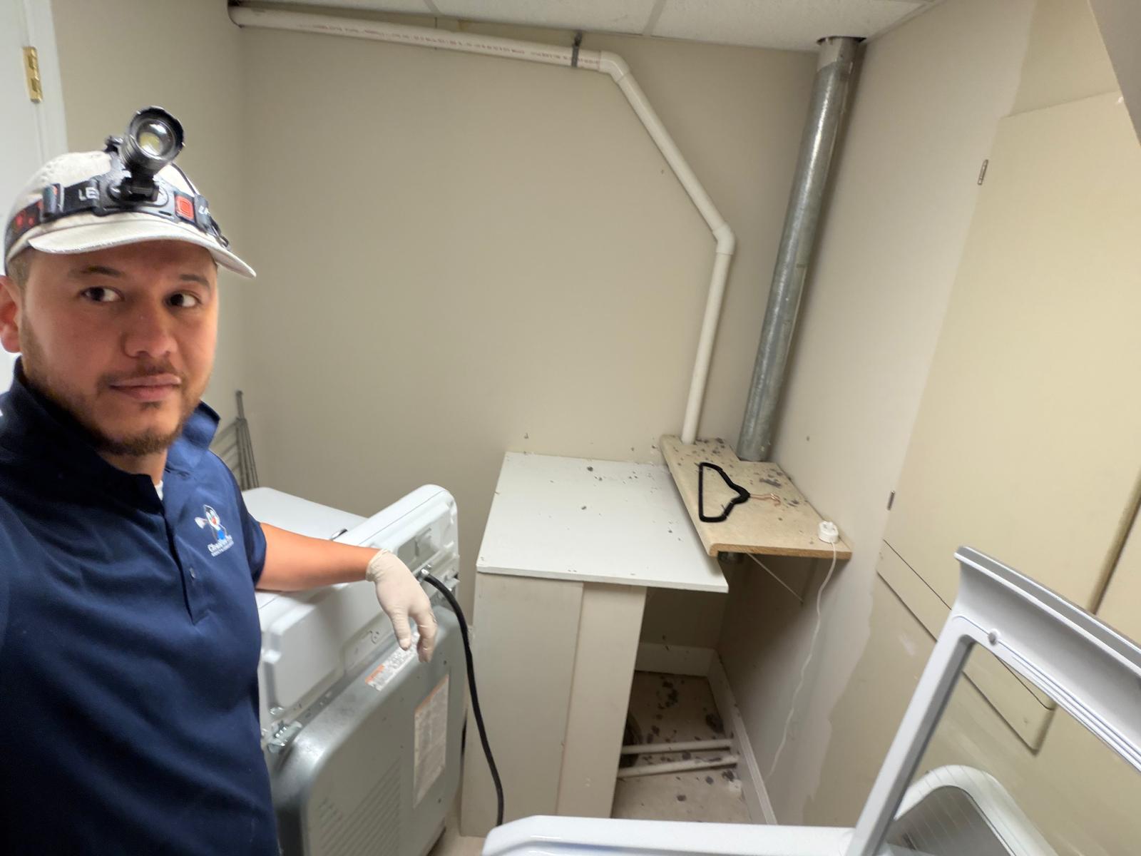 Technician inspecting belt-driven commercial dryers in a building mechanical room