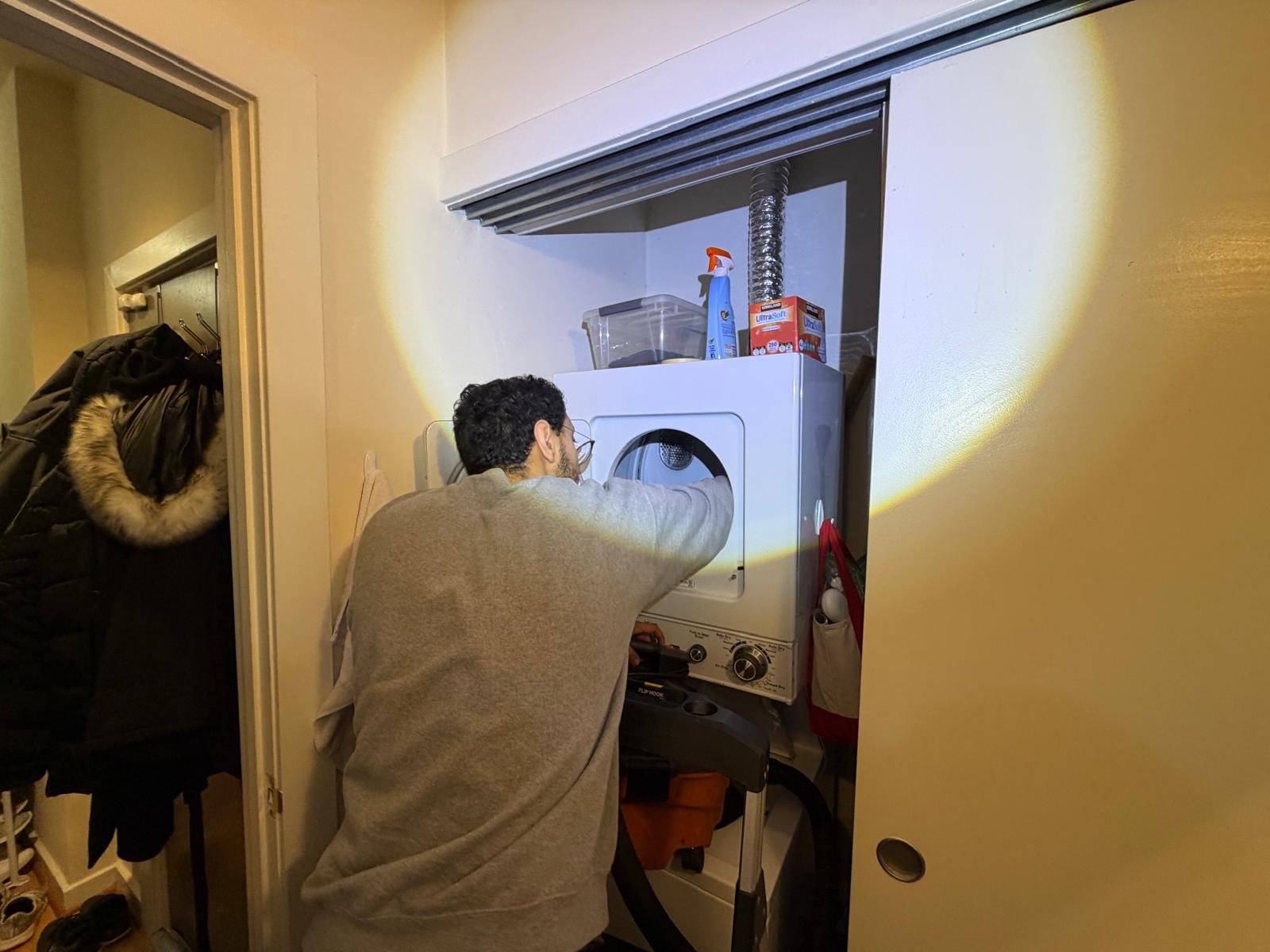 Technician repairing the control board of a stacked Whirlpool dryer
