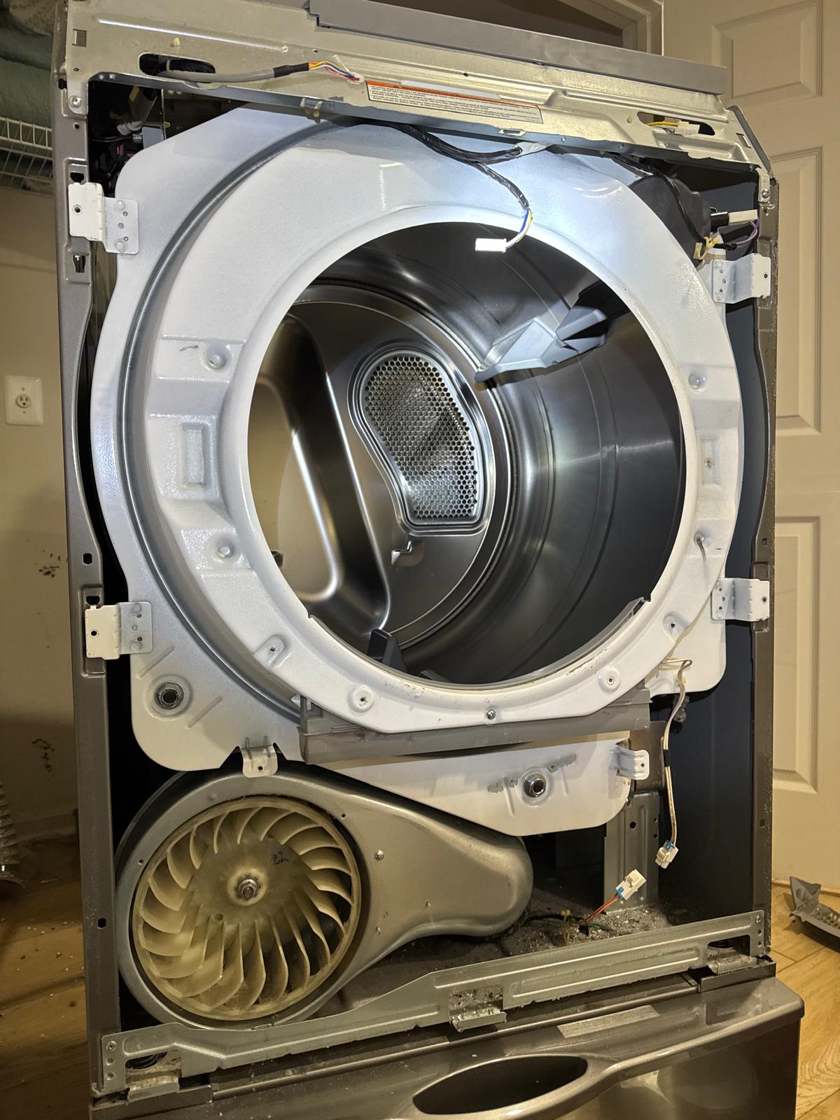 Open clothes dryer showing the drum, blower wheel, and felt seal during a repair