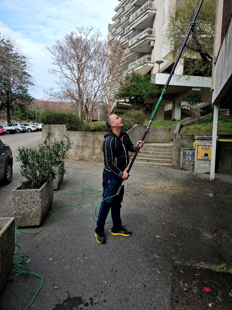 Radnik pere višekatnu stambenu zgradu telescopskom motkom