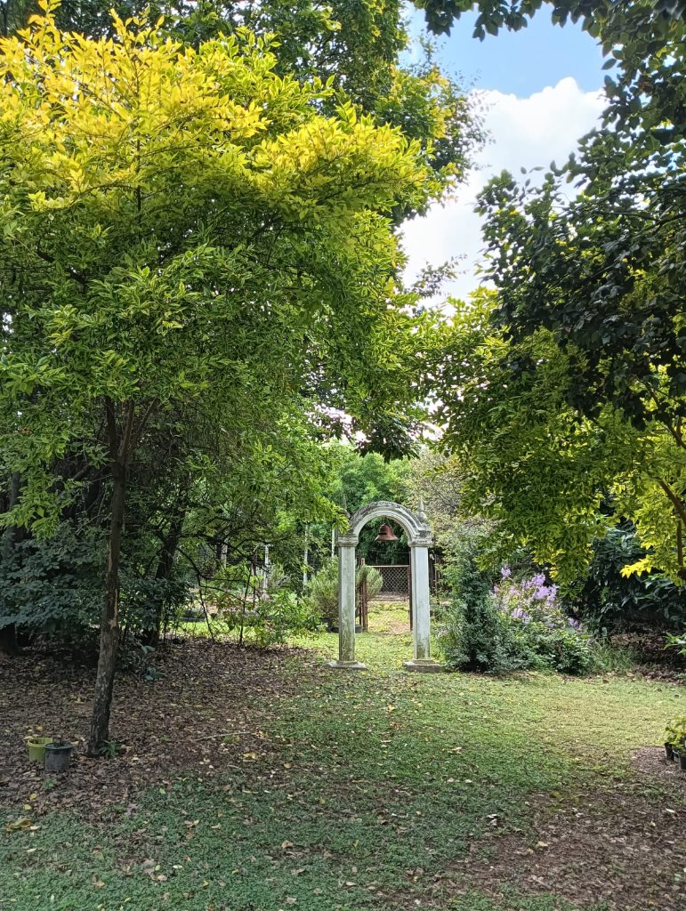 Natural Dynamix garden venue featuring an ornate stone archway surrounded by lush greenery