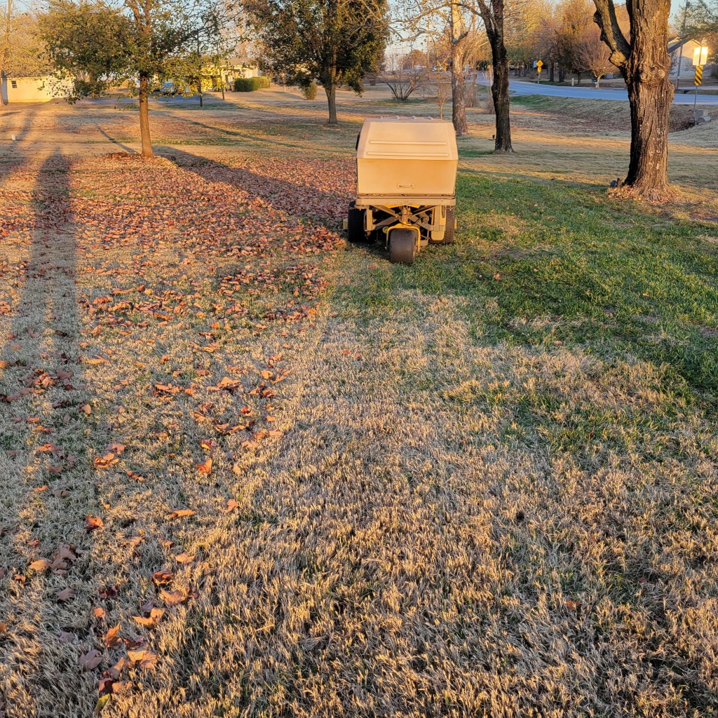 Backyard lawn striped with mower and white vinyl fence
