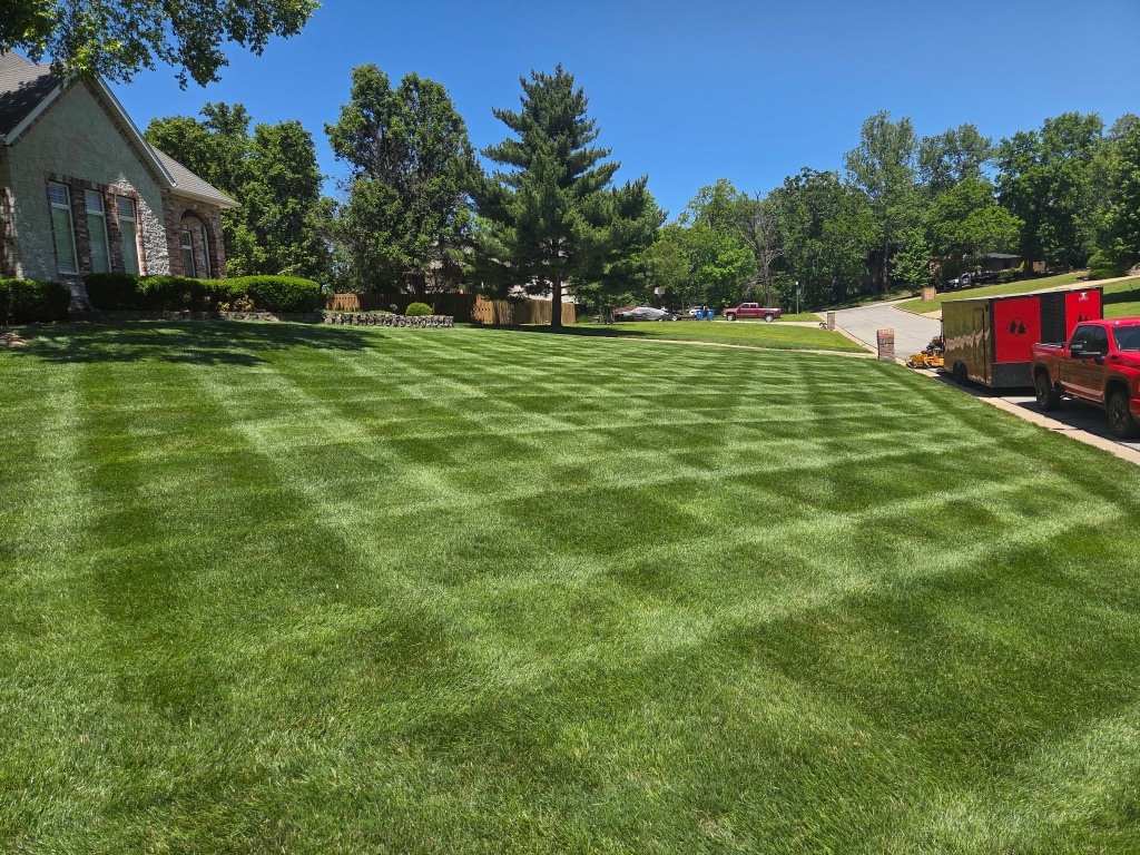 Striped lawn with red truck and trailer parked on street