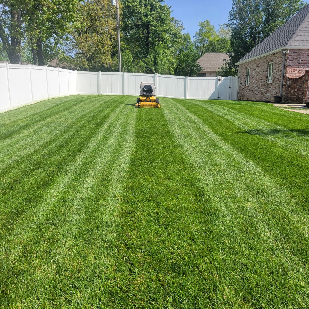 Estate striped lawn with Tudor stone home and colorful garden bed