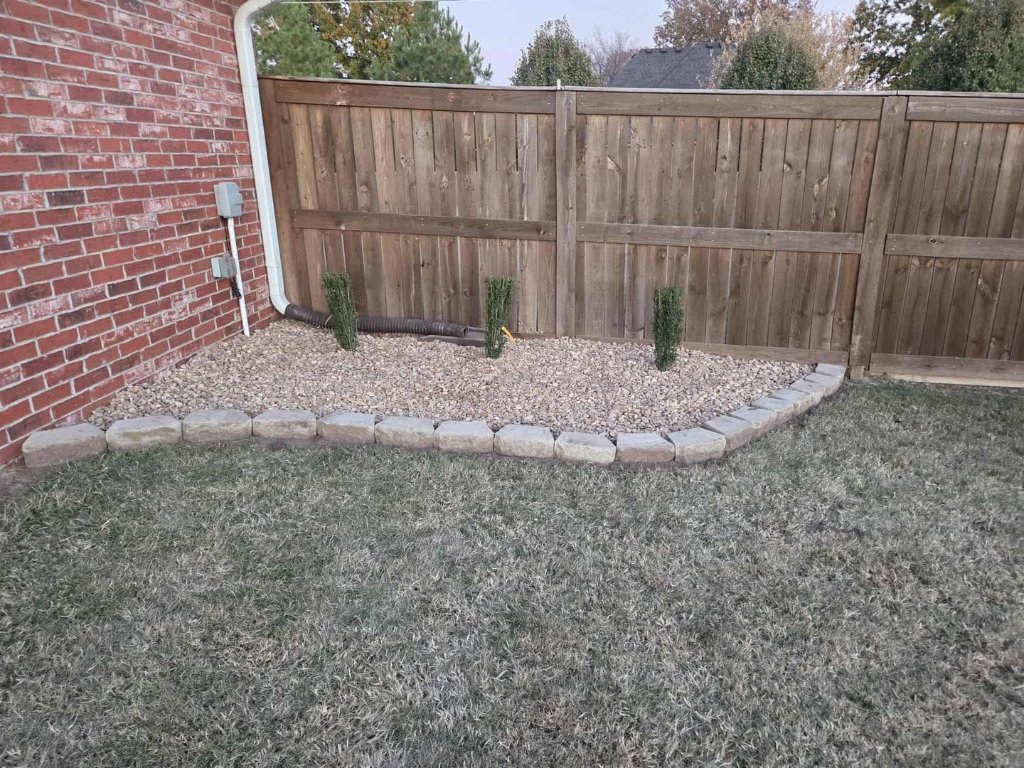 White gravel bed with sharp black edging and flower pots