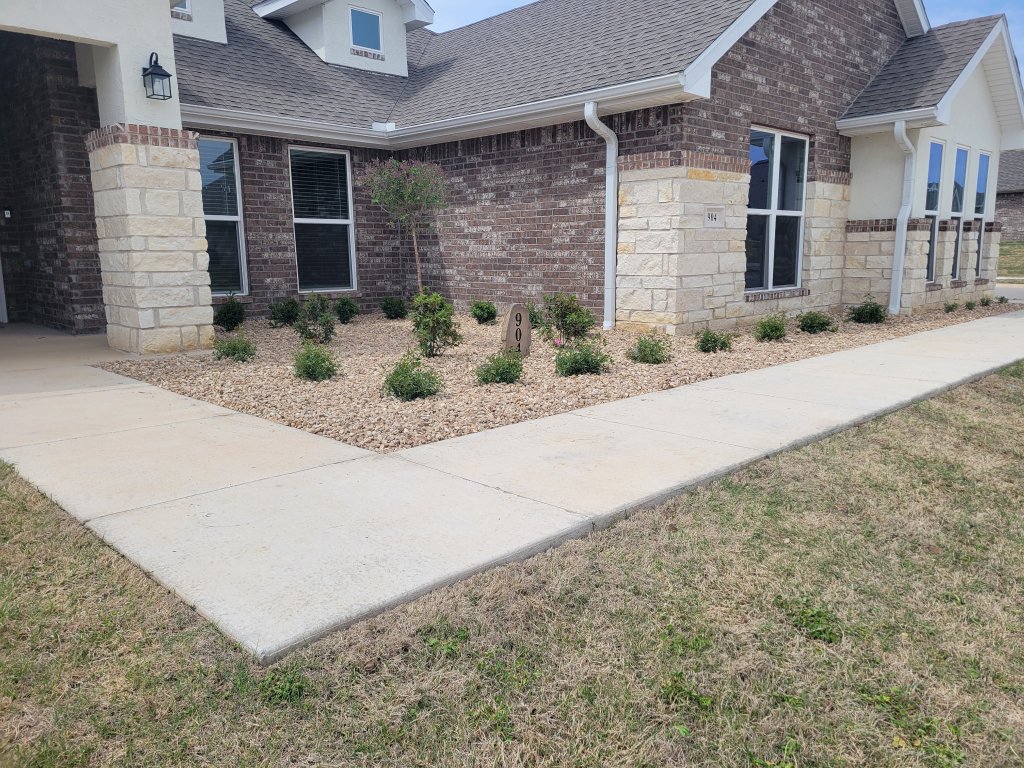 New home landscaping with gravel bed, shrubs, and brick facade