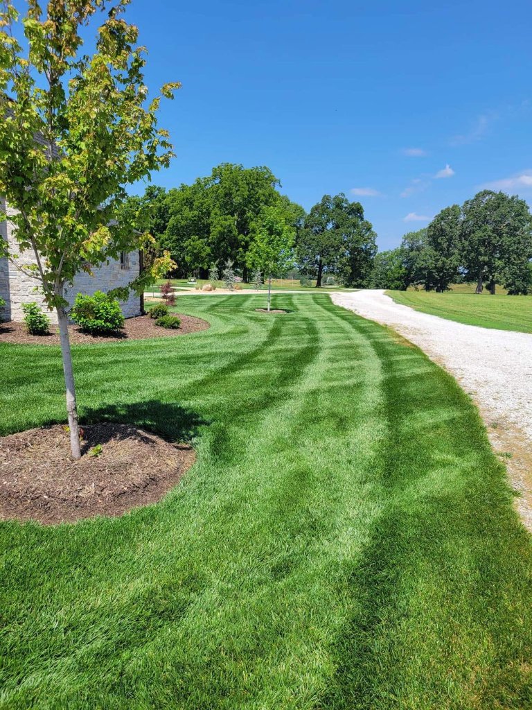 Rural property lawn with curved driveway and landscape beds