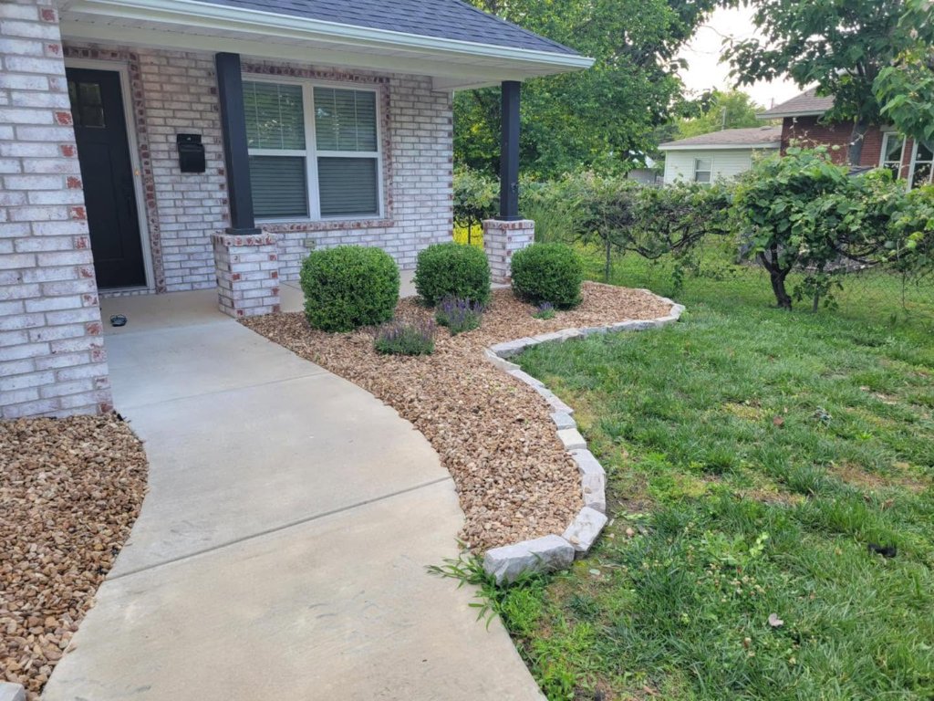 Rock landscape bed with evergreen shrubs and stone border