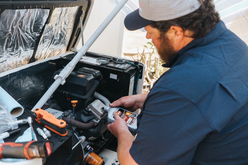 Never Dark Carolinas technician performing oil service on a home standby generator