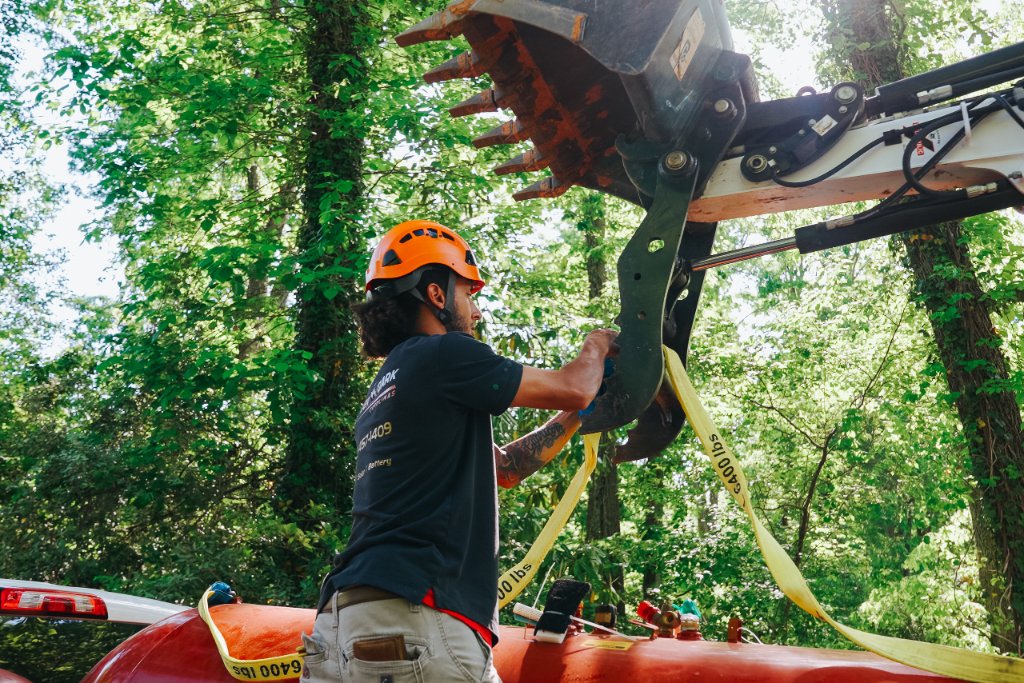 Never Dark Carolinas technician securing a propane tank with lifting straps during installation