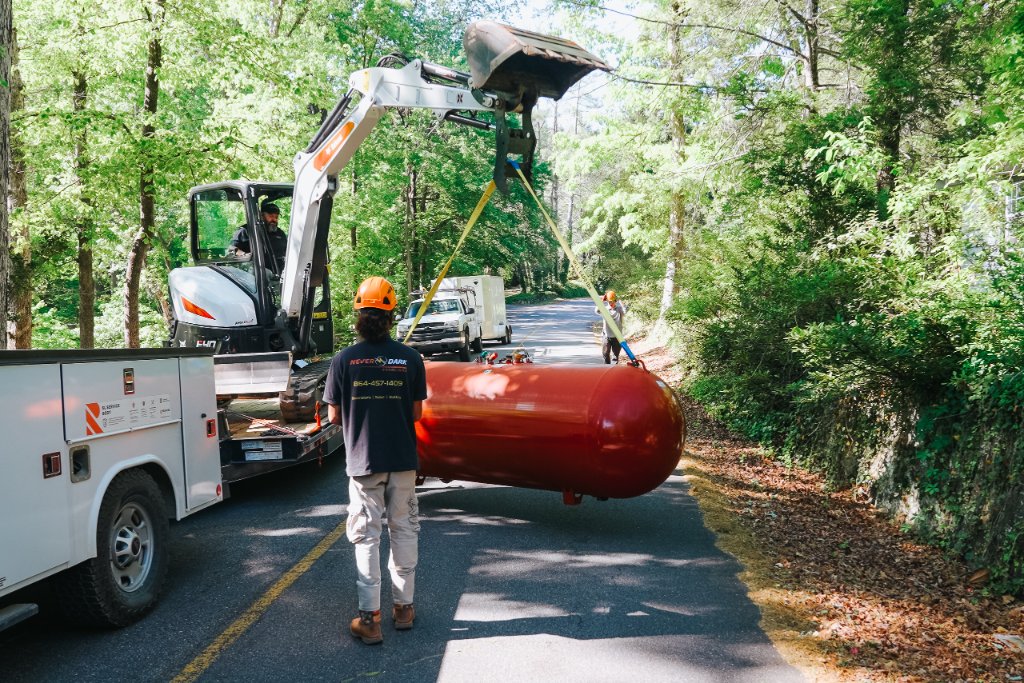 Never Dark Carolinas excavator lifting a propane tank into place on a South Carolina residential road