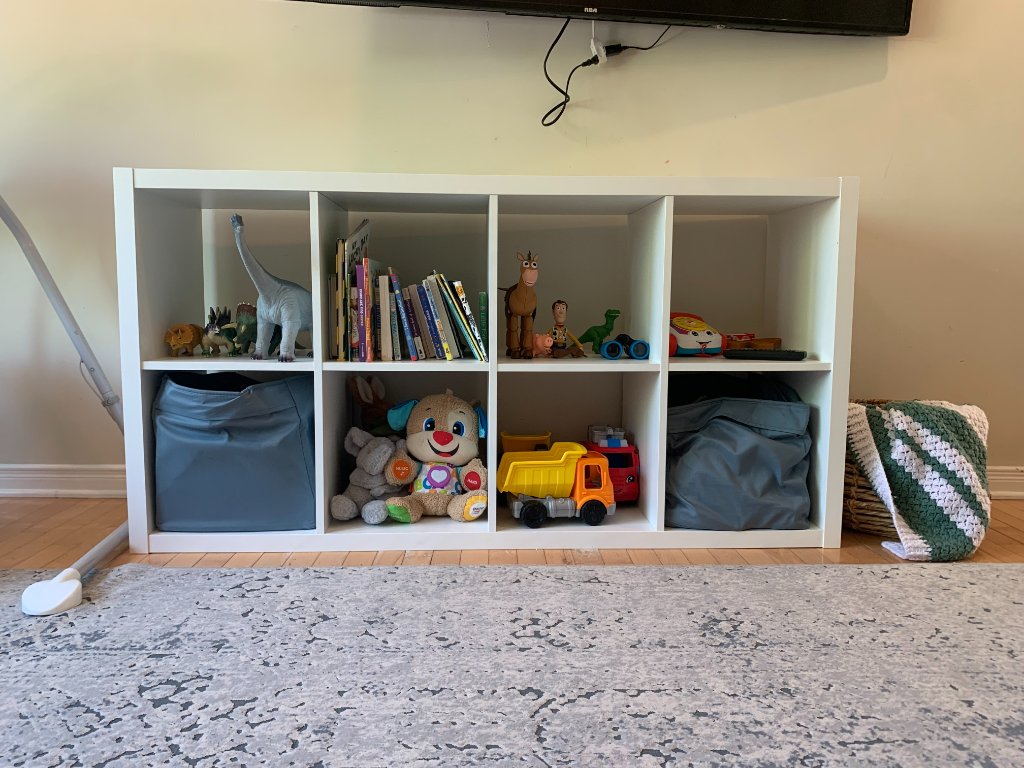 Eight-cube organizer shelf filled with toys, books, and storage bins in the playroom