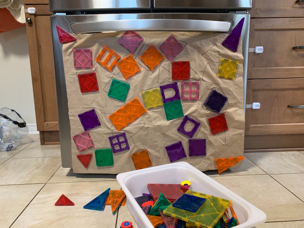 Colorful translucent magnetic geometric tiles arranged on kraft paper on the fridge