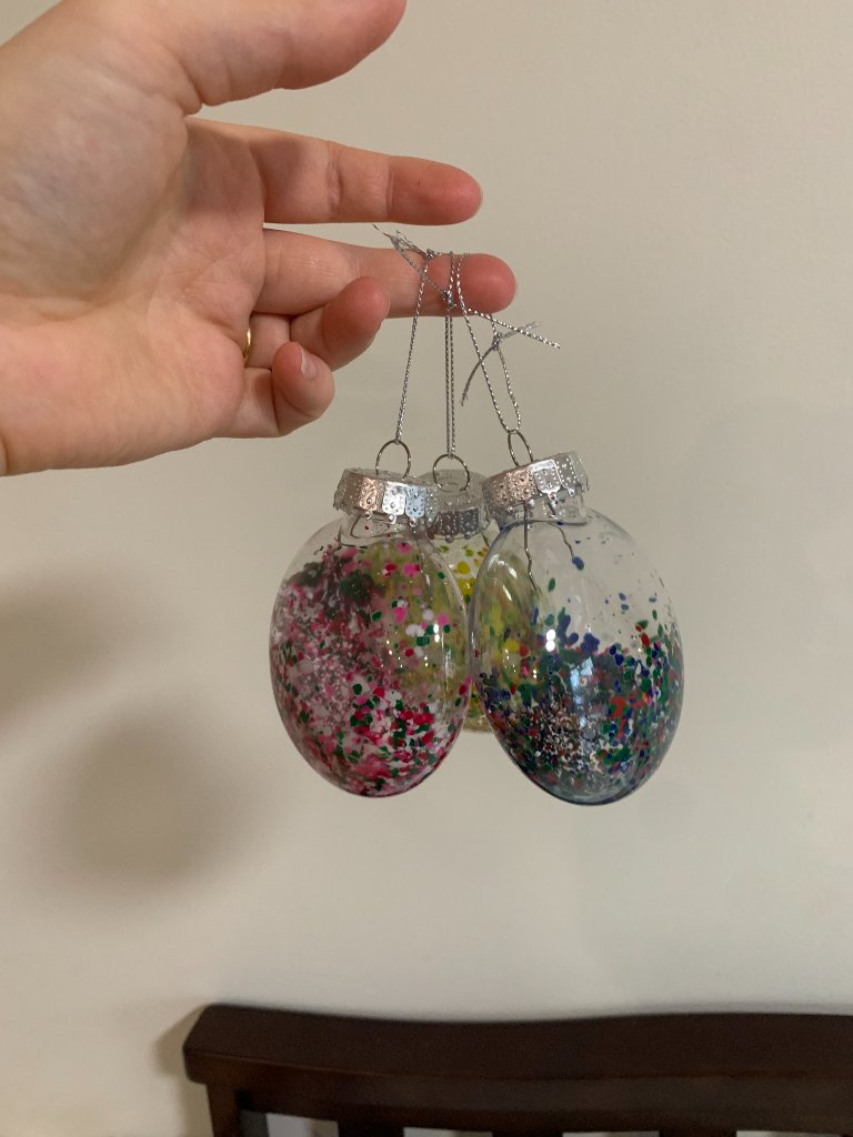Clear bulb ornaments filled with colorful confetti specks held up by hand