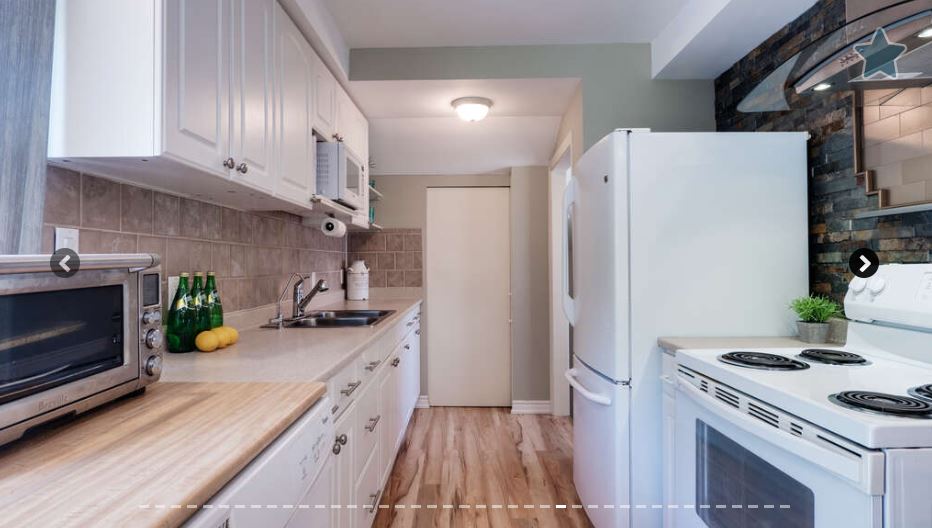 Kitchen with white cabinetry and stone wall