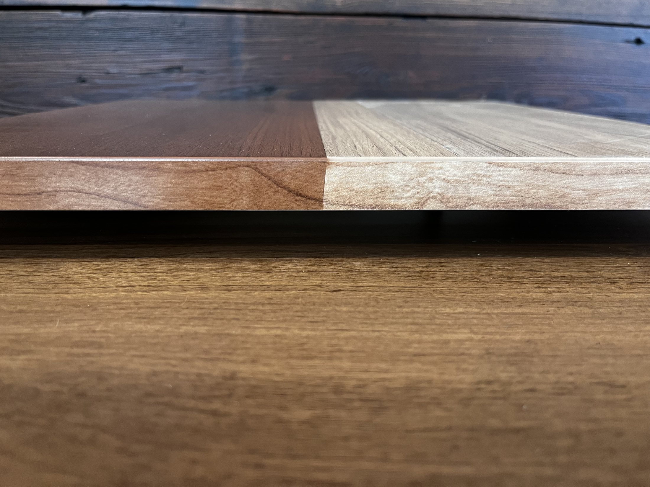 Two wood veneer samples laid edge to edge showing a contrast in tone and grain.