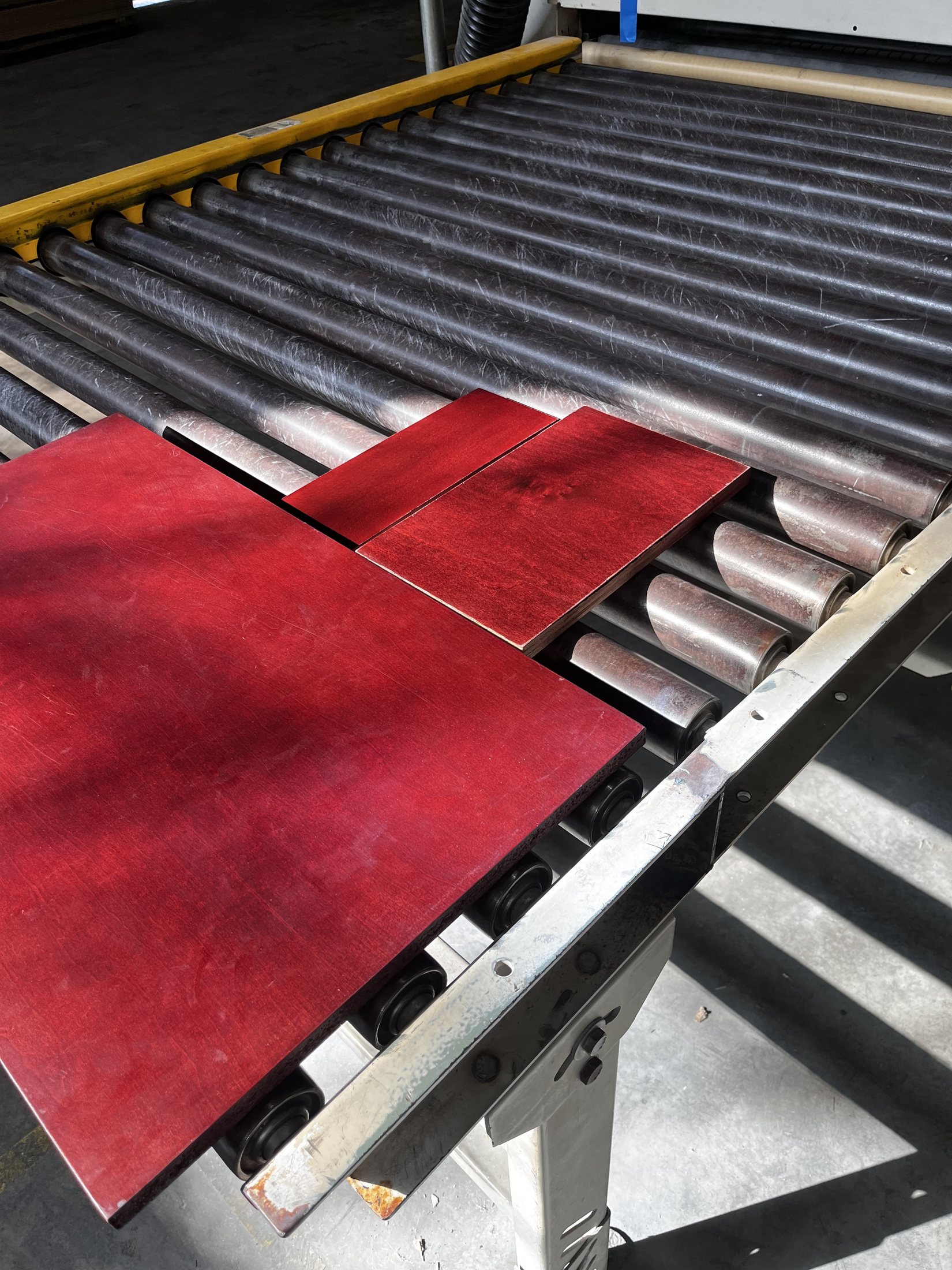 Two deep-red finished panels resting on a roller conveyor.